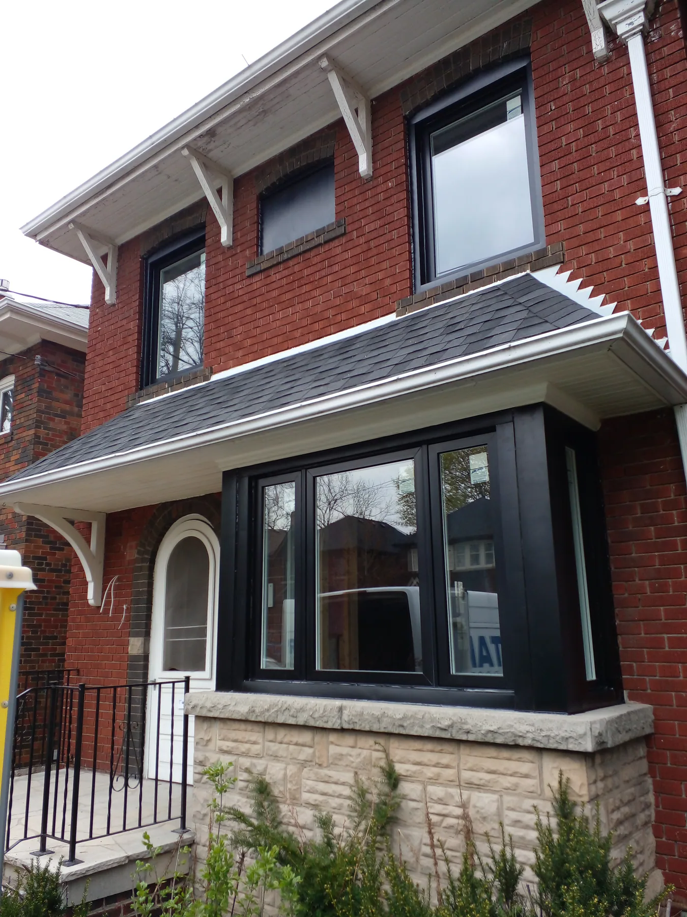 Black bay and upper-storey windows installed on a red brick home